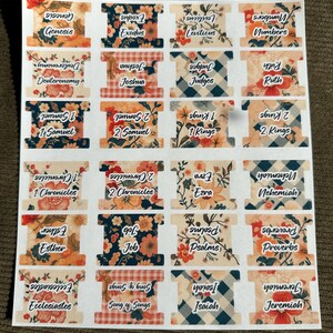 May include: A sheet of Bible book tabs with floral, plaid, and patterned designs. Each tab features the name of a book of the Bible in white text. The tabs are in various colors, including orange, blue, and red.