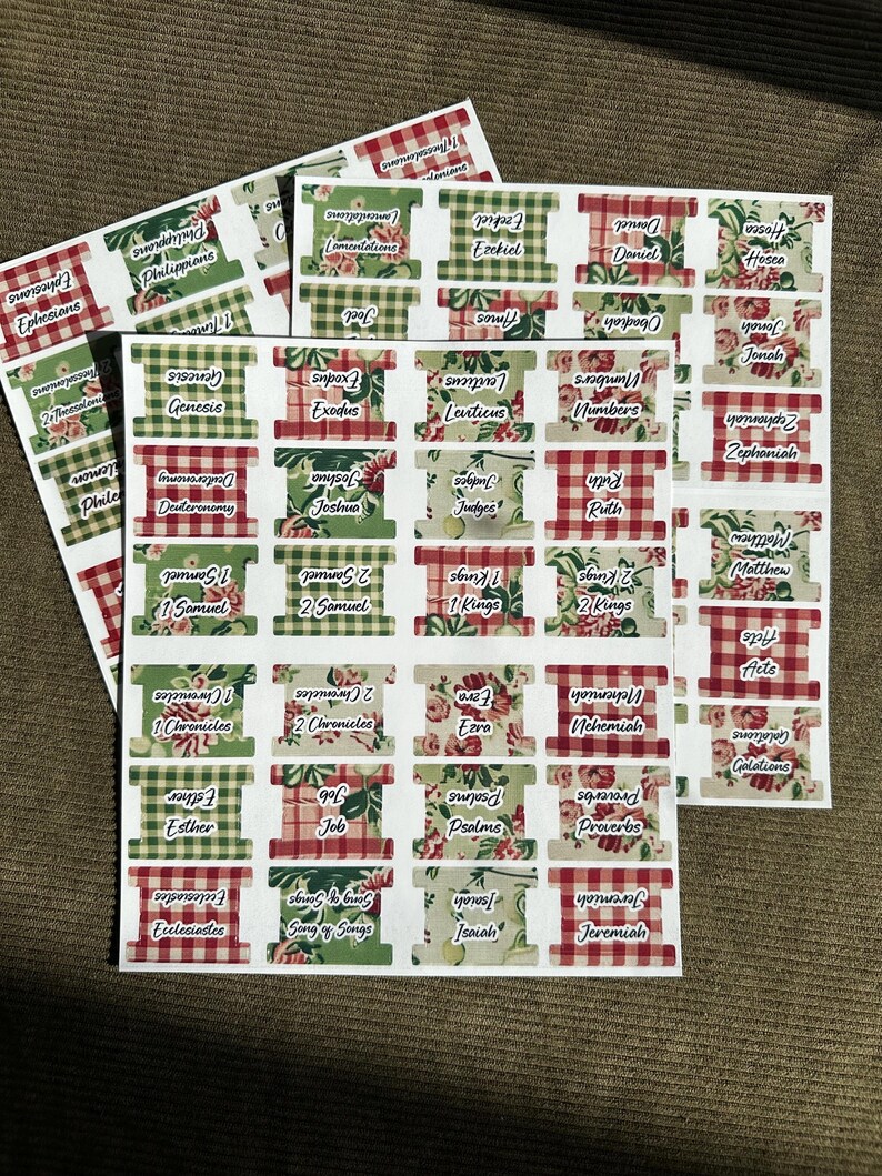 May include: Sheets of Bible book labels with floral and gingham patterns. Each label features a book name, such as Genesis or Psalms, in a clear font. The labels are in red, green, and white.