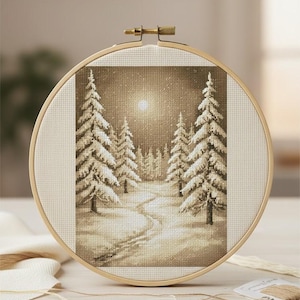 May include: A cross-stitch embroidery depicting a winter scene with snow-laden pine trees and a winding path. The artwork is framed in a round wooden hoop, presenting a sepia-toned view of a snowy forest under a bright moon.