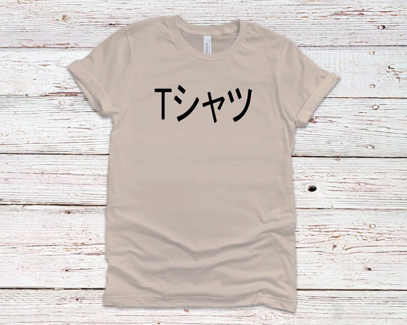 May include: A beige t-shirt with the Japanese text "Tシャツ" printed in black on the front.
