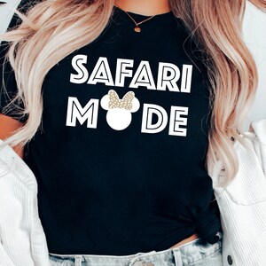 K&ouml;nnte beinhalten: Schwarzes T-Shirt mit wei&szlig;em Text "Safari Mode" und einer wei&szlig;en Silhouette von Mickey Mouse mit einer goldenen Glitzer Schleife.