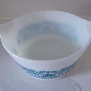 May include: A white mixing bowl with a blue and white floral pattern. The bowl has a lip on either side.