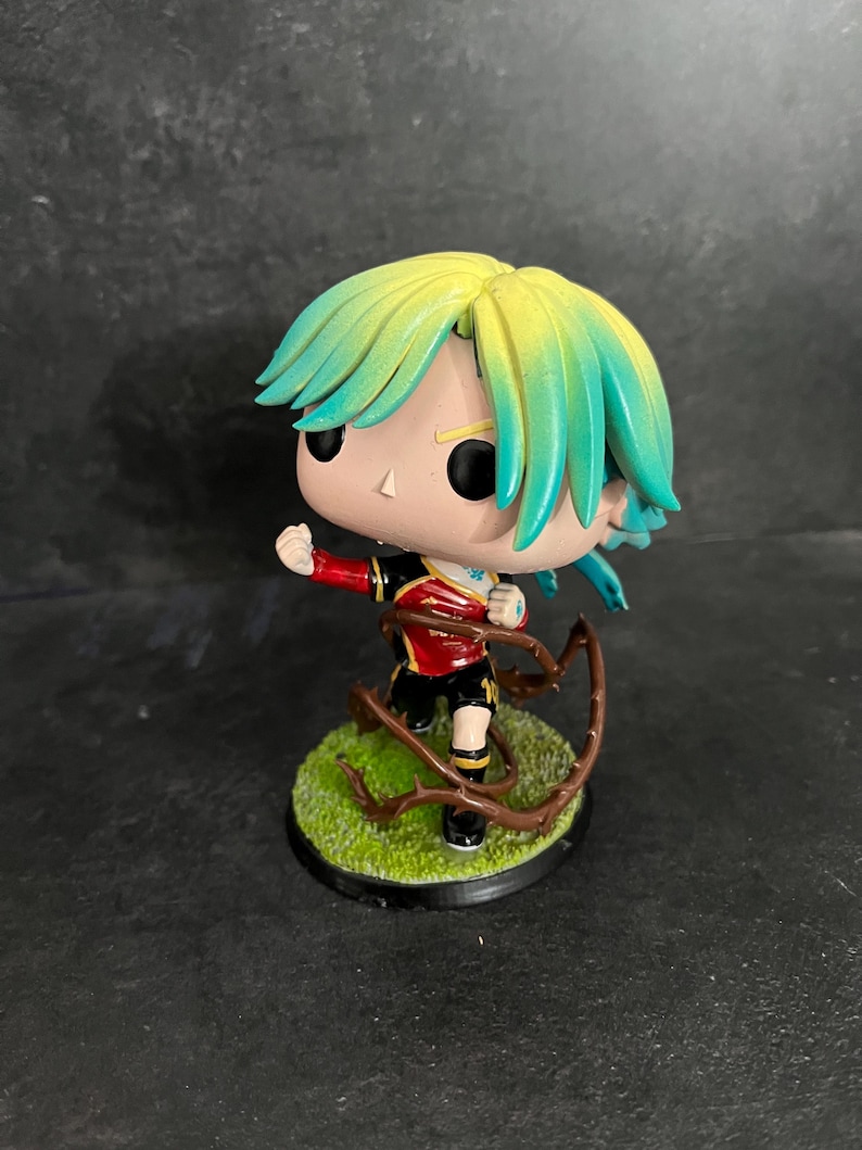 May include: A green and yellow haired figurine with a red and gold shirt, black shorts, and brown vines around its legs. The figurine is standing on a green base with brown vines.
