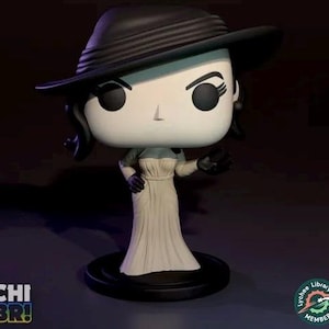 May include: A Funko Pop vinyl figure of a character wearing a black hat and a long white dress. The figure has a stylized design with large black eyes and a small nose. The figure is on a black base.