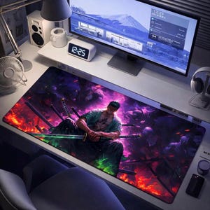 May include: A rectangular desk mat with a colourful anime-style illustration of a character with swords, set against a fiery backdrop. The mat is designed to protect the desk surface and improve the user's workspace.