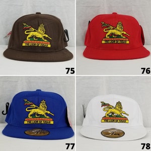 Puede incluir: Cuatro gorras de béisbol de diferentes colores con un logotipo de León de Judá bordado en la parte delantera. El león es amarillo con una bandera verde, roja y amarilla. El texto "The Lion of Judah" está debajo del león. Las gorras son marrón, roja, azul y blanca.