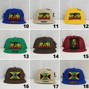 Puede incluir: Diez gorras de béisbol diferentes con varios diseños que presentan la imagen de Bob Marley y el texto "Bob Marley". Algunas gorras también presentan el texto "Freedom".