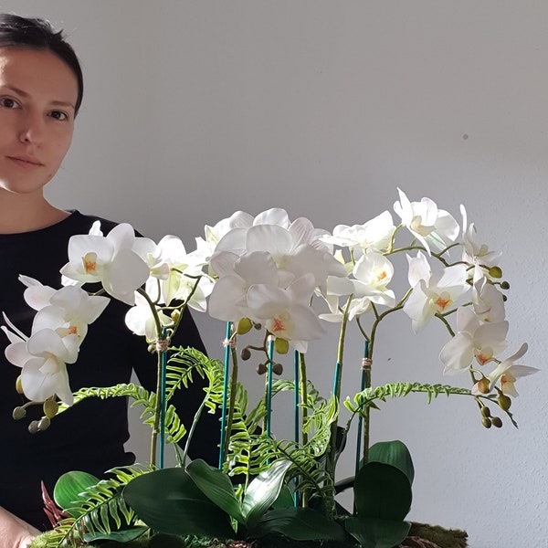 Plantas de orquídeas blancas Phalaenopsis en un tazón blanco. Florero de hojas con arreglo de orquídeas artificiales falsas.