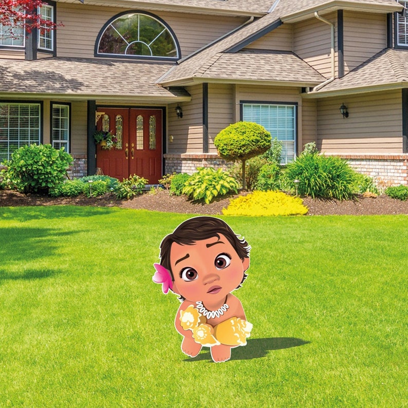 May include: A flat, cutout yard sign featuring a cartoon illustration of a baby with dark brown hair, a pink flower tucked behind one ear, and a white shell necklace, wearing a yellow shell-patterned garment while sitting on green grass.