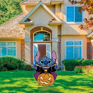 May include: A blue and purple cartoon character dressed as a vampire holding a jack-o'-lantern. The character is standing in front of a house with a green lawn.