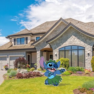 May include: A blue cartoon character with large ears, a green grass skirt, and a lei, stands on a green lawn in front of a large house with a stone facade. The character is smiling and waving, with a blue sky and clouds in the background.