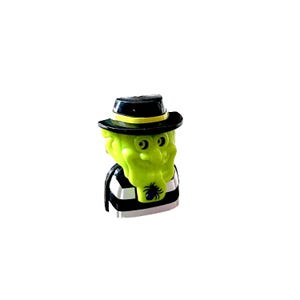 May include: A small figurine featuring a lime green character wearing a black hat with a yellow band. The character has a wide grin and is dressed in a black and white striped shirt. A small black spider graphic is printed on the chest area.