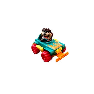 May include: A small toy vehicle in teal with orange flame decals, featuring a brown Tasmanian Devil character in the driver seat. The car has bright red wheels, a yellow front grille, and an orange front bumper, with yellow side exhaust pipes.