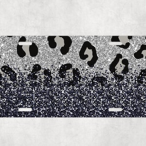 May include: A silver and black glitter license plate with a leopard print design.