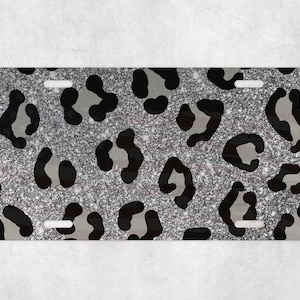 May include: A silver glitter license plate with a black and gray leopard print design.