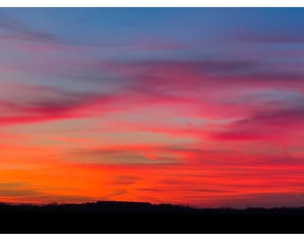 May include: A vibrant sunset sky with shades of pink, orange, and blue. The clouds are layered and create a dramatic effect.