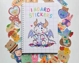 May include: A colorful sticker sheet with a white dragon with blue, pink, and purple accents. The sticker sheet has a grid pattern and the text "I HOARD STICKERS" in rainbow colors. The sticker sheet is surrounded by other stickers with various designs, including animals, hearts, and flowers.