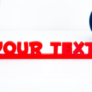 Pode incluir: Letras de plástico vermelho soletrando "YOUR TEXT" em uma superfície branca.