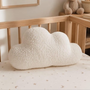 May include: A cloud-shaped decorative cushion made of a soft, off-white textured fabric. The cushion features a rounded, multi-lobed silhouette that mimics the appearance of a fluffy cloud, with a plush, high-pile surface texture throughout.