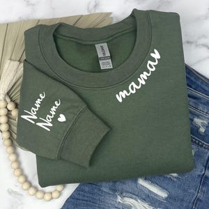 May include: A green sweatshirt with the word "mama" on the front and the word "Name" on the sleeve. The sweatshirt has a white heart on the sleeve.