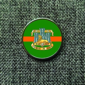 May include: A circular metal badge with a green and orange design. The badge features a lion and castle emblem, with the words "SEMPER FIDELIS" and "MARABOUT PRIMUS IN INDIS".
