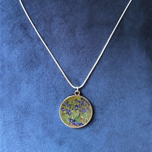 Peut inclure: Un collier en chaîne argent avec un pendentif rond représentant une peinture d'iris violets sur fond vert.