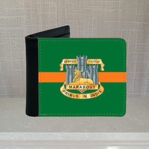 May include: A black and green bi-fold wallet. The green front panel has an orange stripe and a crest with a lion, castle, and text. The text includes "SEMPER FIDELIS", "MARABOUT", and "PRIMUS IN INDIS". The wallet is a classic design.
