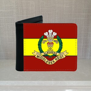 May include: A black and red bi-fold wallet with a regimental crest design. The crest includes the words "ALBUHERA MIDDLESEX REGI" and is surrounded by a green wreath. The wallet has a stitched border.