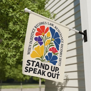 May include: A rectangular flag with a floral design in red, blue, yellow, and purple. The flag has the text "WHEN INJUSTICE BECOMES LAW, RESISTANCE BECOMES DUTY" and "STAND UP, SPEAK OUT" in black.