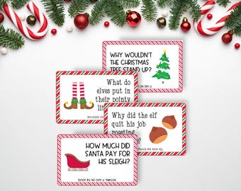 May include: A set of four rectangular Christmas joke cards with red and green striped borders. Each card features a holiday-themed question and illustration, including a Christmas tree, elf legs, roasted chestnuts, and a red sleigh with text.