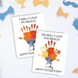 May include: Two white Father's Day cards with handprint art and the text "I Grill-y Love My Abuelo!" and "We Grill-y Love Our Abuelo!". The cards feature a watercolor grill design and the words "Happy Father's Day". Decorative cutouts surround the cards.