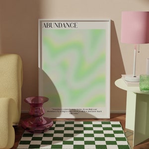 May include: A framed print with a green and white abstract design and the word "ABUNDANCE" in black text at the top. The quote "Abundance comes in many forms, do not limit your abundance by trying to control how it will flow, just know that it will come." is printed in black text at the bottom of the print.
