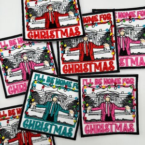 May include: A set of six embroidered iron-on patches featuring a person standing in front of a building with Christmas lights. The text on the patches reads "I'll be home for Christmas".