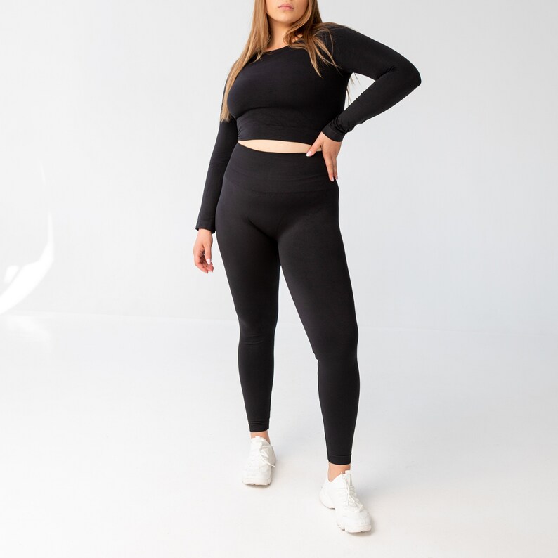 May include: A black long-sleeved crop top and matching leggings. The top has a round neckline and the leggings are seamless.