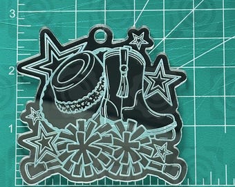 May include: A black acrylic charm featuring a cowboy hat, cowboy boot, stars, and pom-poms. The charm has a small hole at the top for hanging. The text "thehillscrafts.com" is visible at the top.