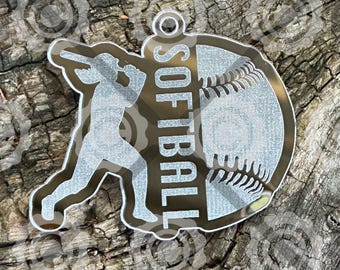 May include: A clear acrylic softball keychain featuring a batter silhouette and a softball design. The word "SOFTBALL" is vertically displayed. The keychain has a small hole for attachment. The background is a wooden surface.
