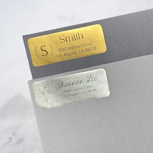 May include: Two gold and silver return address labels with a floral design and the names "Smith" and "Shannon Lee" with their respective addresses.