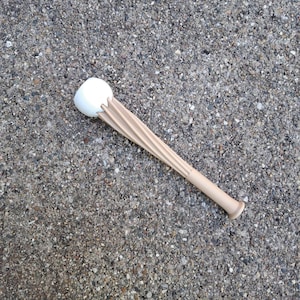 Op de afbeelding: Een beige en witte flesstopper met een uniek ontwerp. De stopper heeft een witte, afgeronde bovenkant en een beige, getextureerde handgreep. De handgreep heeft een reeks verticale ribbels. De stopper is ontworpen om in een fles te passen.