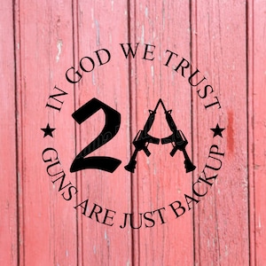 May include: Black graphic with the text "IN GOD WE TRUST" and "GUNS ARE JUST BACKUP" encircling the number "2A" and two rifles. The design is set against a weathered, red wooden background.