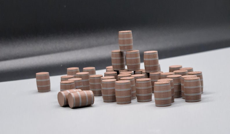 Puede incluir: Una colecci&oacute;n de barriles de madera en miniatura, apilados y dispuestos en forma de pir&aacute;mide. Los barriles est&aacute;n pintados de marr&oacute;n con aros pintados de blanco.