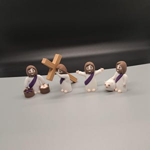 May include: Four small figurines of people dressed in white robes with purple sashes. One figure carries a wooden cross, another carries a basket, another carries a lamb, and the last figure has their hands raised in the air.