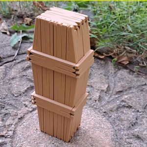 Puede incluir: Un modelo impreso en 3D de un ataúd de madera. El ataúd está hecho de tablones de madera y tiene un diseño sencillo. El modelo está impreso en color marrón claro. La imagen está etiquetada como "ARCHIVO DIGITAL .STL".