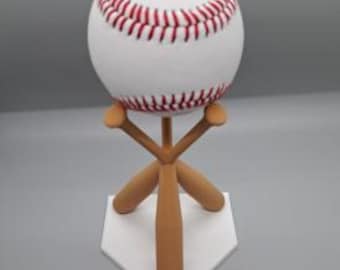 May include: A white baseball with red stitching sits on a white base with three wooden baseball bats.