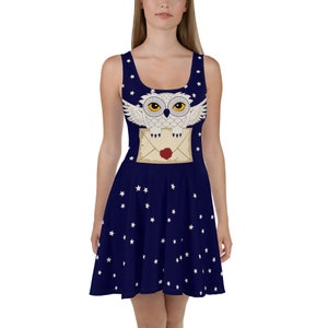 May include: A navy blue dress with a white owl and a letter design. The dress has a white star pattern.