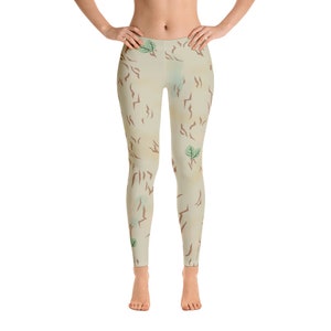 May include: Beige leggings with a camouflage pattern featuring brown and green accents. The pattern resembles a desert landscape with small trees.