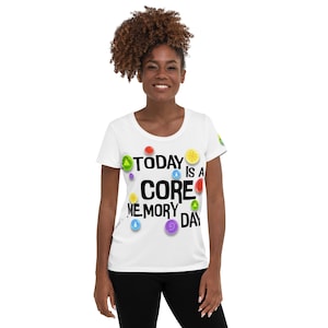 May include: White t-shirt with a scoop neck and short sleeves. The shirt has a graphic print that says "TODAY IS A CORE MEMORY DAY" with colorful circles around the text.