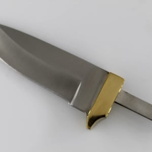 May include: A silver knife blade with a gold-colored handle. The blade is sharp and pointed, and the handle is smooth and rounded. The knife is a blank, meaning it is not yet finished and can be customized.