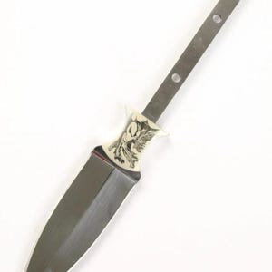 May include: A silver dagger with a decorative handle featuring an etched design. The blade is sharp and pointed.