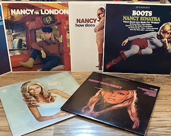 Könnte beinhalten: Eine Sammlung von sieben Schallplatten mit Nancy Sinatra. Die Schallplatten sind in verschiedenen Farben, darunter rosa, blau und schwarz. Die Titel der Schallplatten sind "Boots", "Nancy in London", "How Does", "Count Me In" und "Swingin' With Nancy".