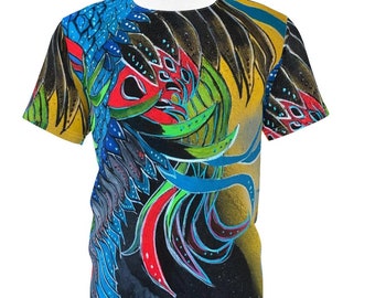 May include: A colorful t-shirt with a graphic print of a stylized bird with blue, green, red, and yellow feathers. The shirt has a white collar and short sleeves. The text "art by alana" is printed on the bottom right corner of the shirt.